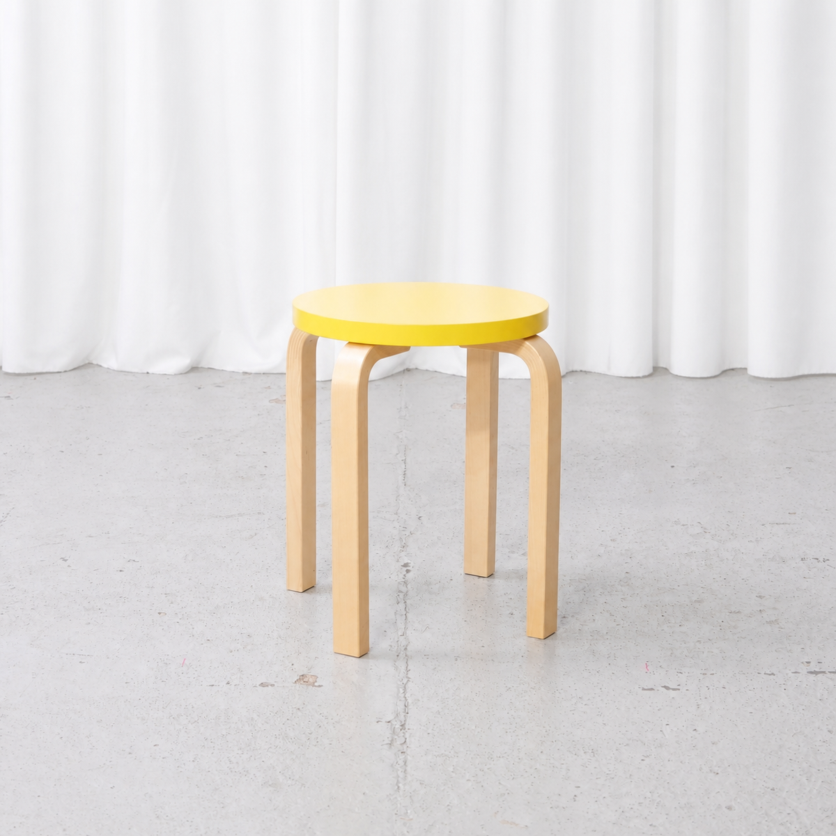 Alvar Aalto E60 stool for Artek with a yellow lacquered seat, front view