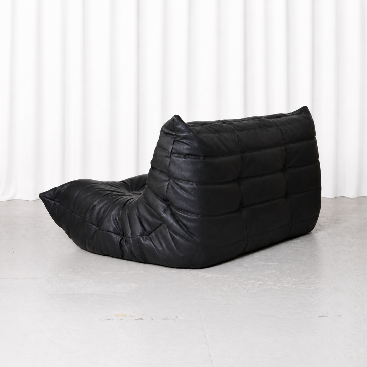 Back three-quarter view of the black Ligne Roset Togo two-seater sofa.
